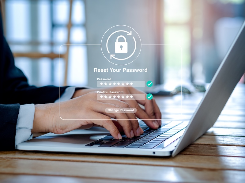 Hands typing on a laptop keyboard with a transparent “Reset Your Password” interface overlay, highlighting fields for entering and confirming a new password, and featuring internet security tools to ensure your information stays protected.