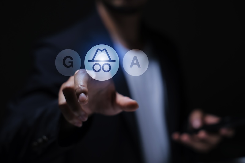A person in a suit points at a glowing incognito mode icon on a transparent screen, with the letters "G" and "A" on either side, highlighting efforts to protect privacy online and enable anonymous browsing.