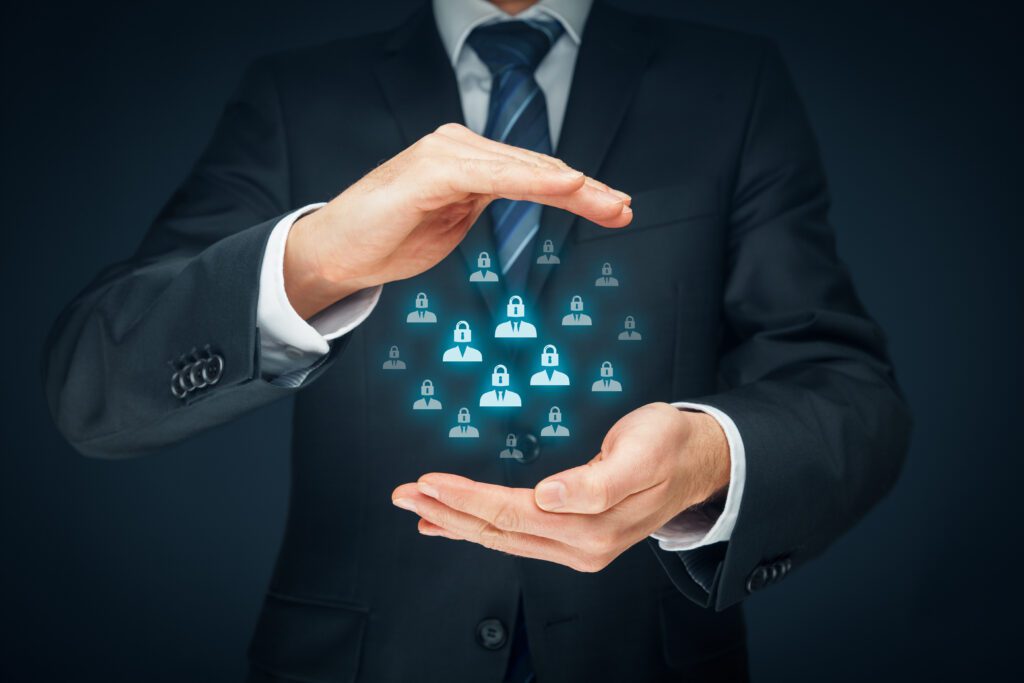 A person in a suit is holding their hands out, creating a protective gesture around a cluster of glowing padlock icons. The image symbolizes cybersecurity or data protection, with a dark background emphasizing the lit lock symbols between their hands.