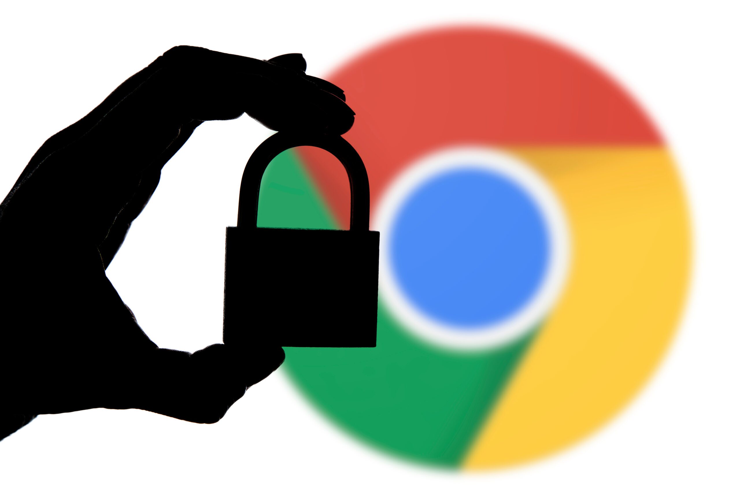 Silhouette of a hand holding a padlock in front of a blurred Chrome logo, symbolizing cybersecurity and internet privacy.