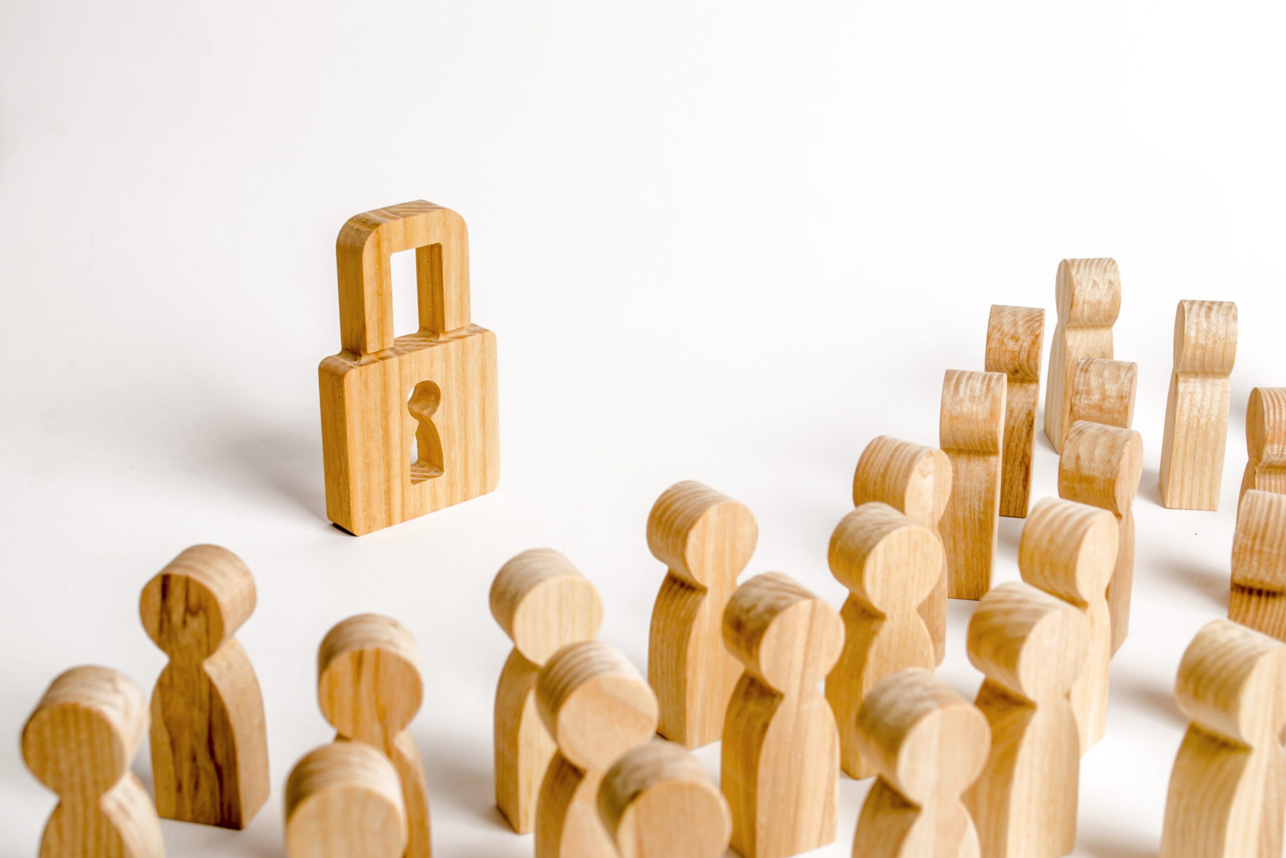 Wooden human figures face a large padlock on a white background, symbolizing security and access control.