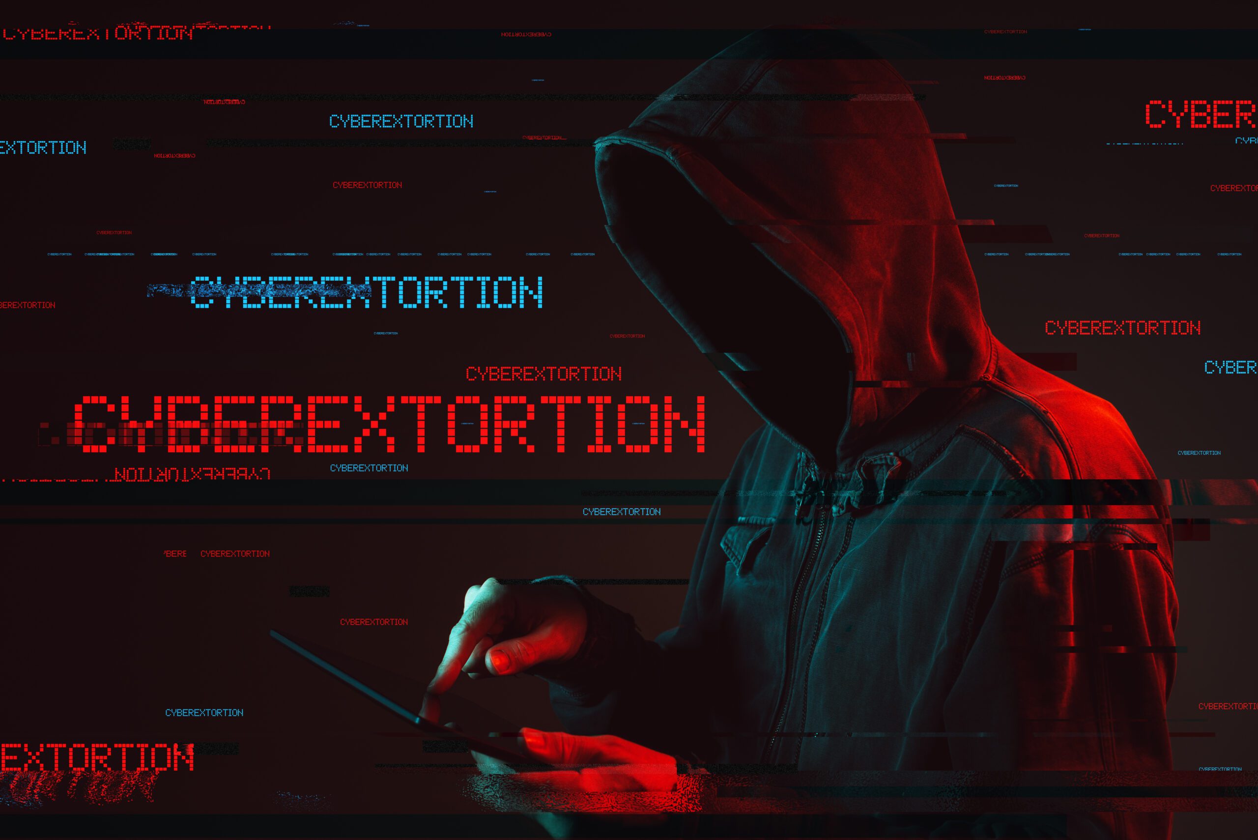 A person in a hooded jacket is using a tablet in a dark room. The scene is overlaid with digital text and glitch effects, featuring the word "CYBEREXTORTION" in blue and red. The atmosphere is tense and technological.