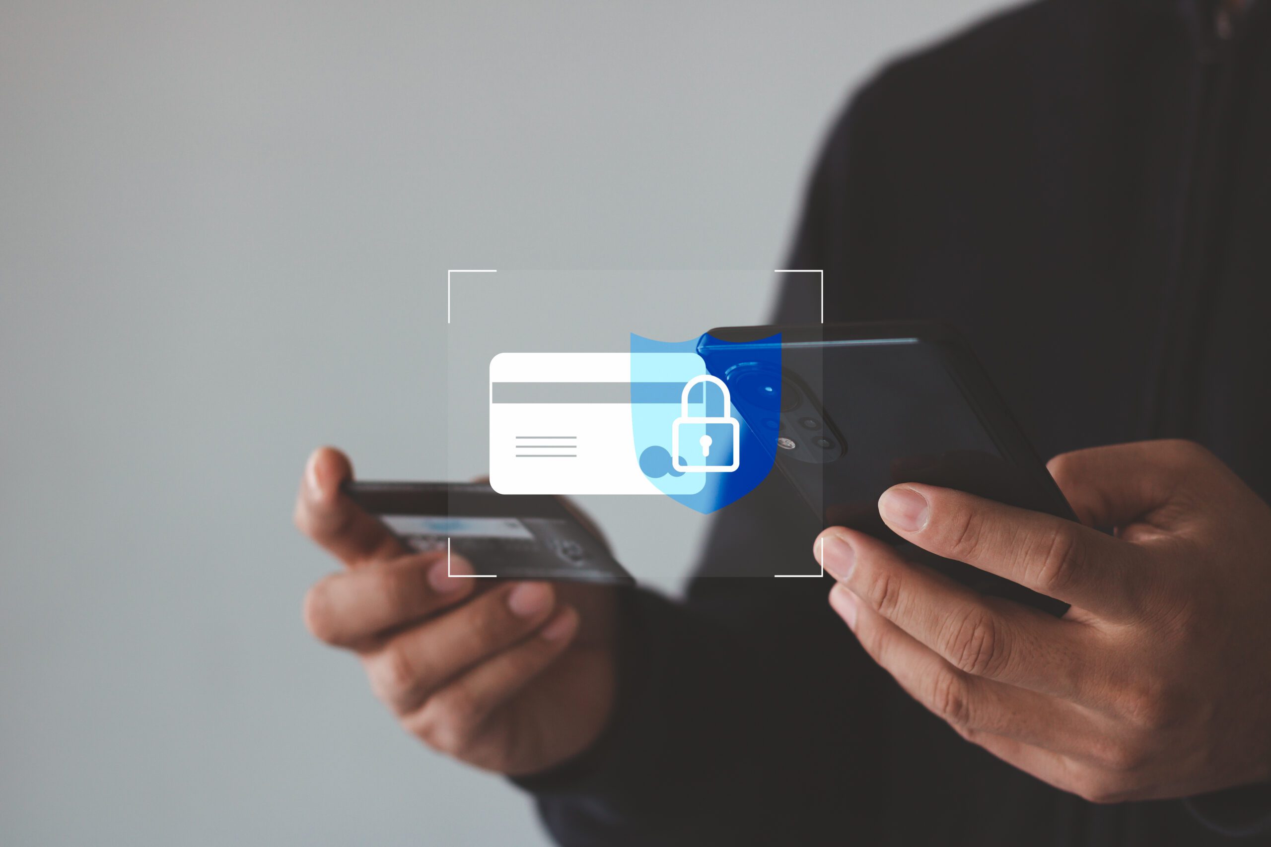 Person holding a smartphone and a credit card, with a digital overlay of a credit card and padlock icon, representing secure online payment or data protection.